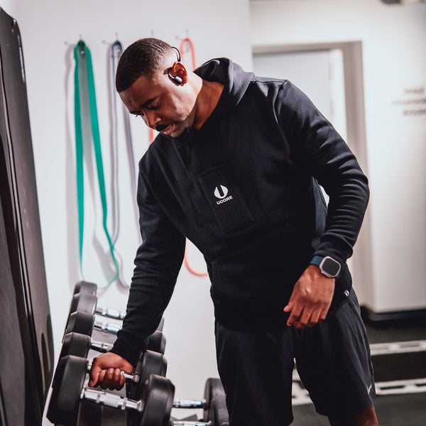 male lifting weights in gym wearing black men's hoodie by ucore