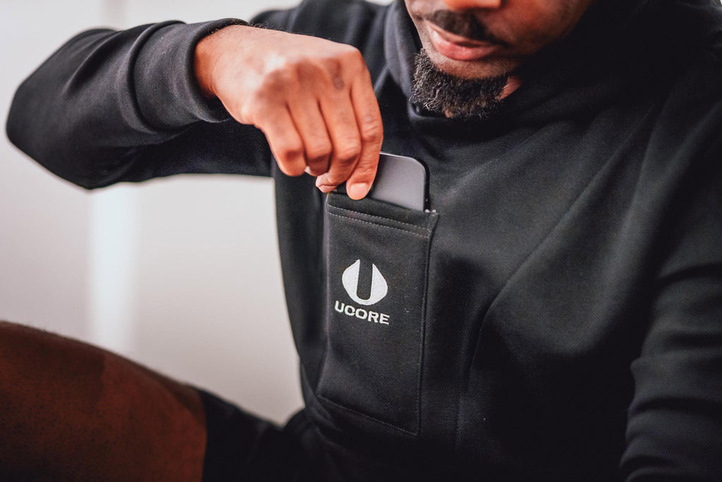 a phone being taken out of the pocket of a black ucore hoodie