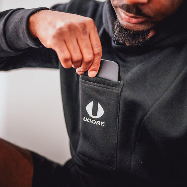 a phone being taken out of the pocket of a black ucore hoodie