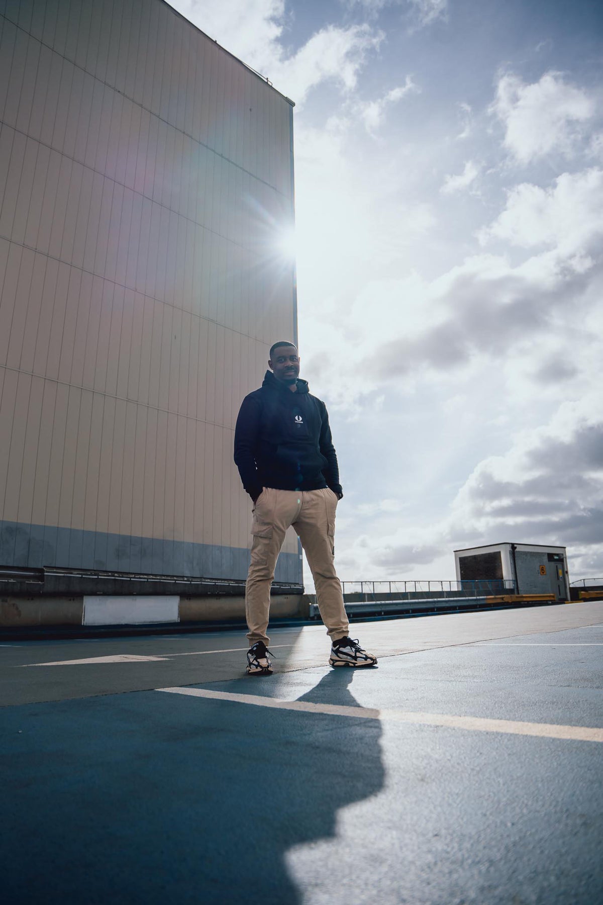 man standing in car park wearing black hoodie by ucore