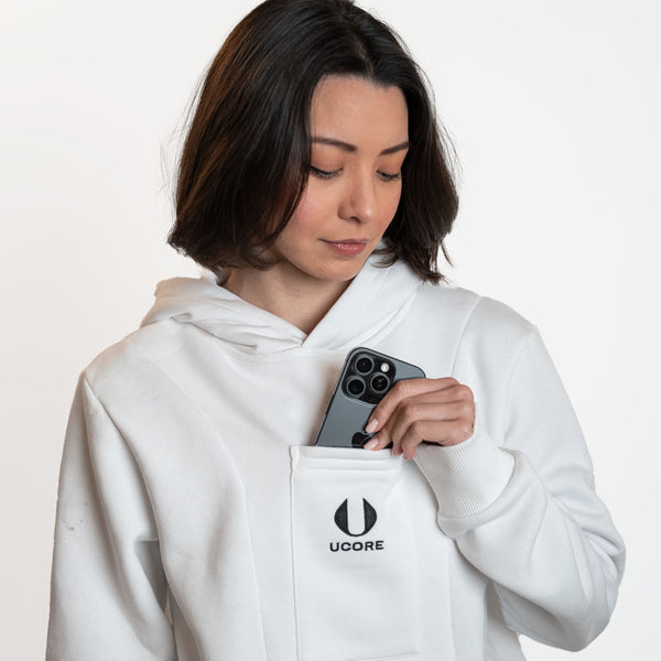model taking phone out of phone pocket of ucore's white women's hoodie