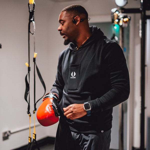 male in gym wearing men's black hoodie designed by ucore