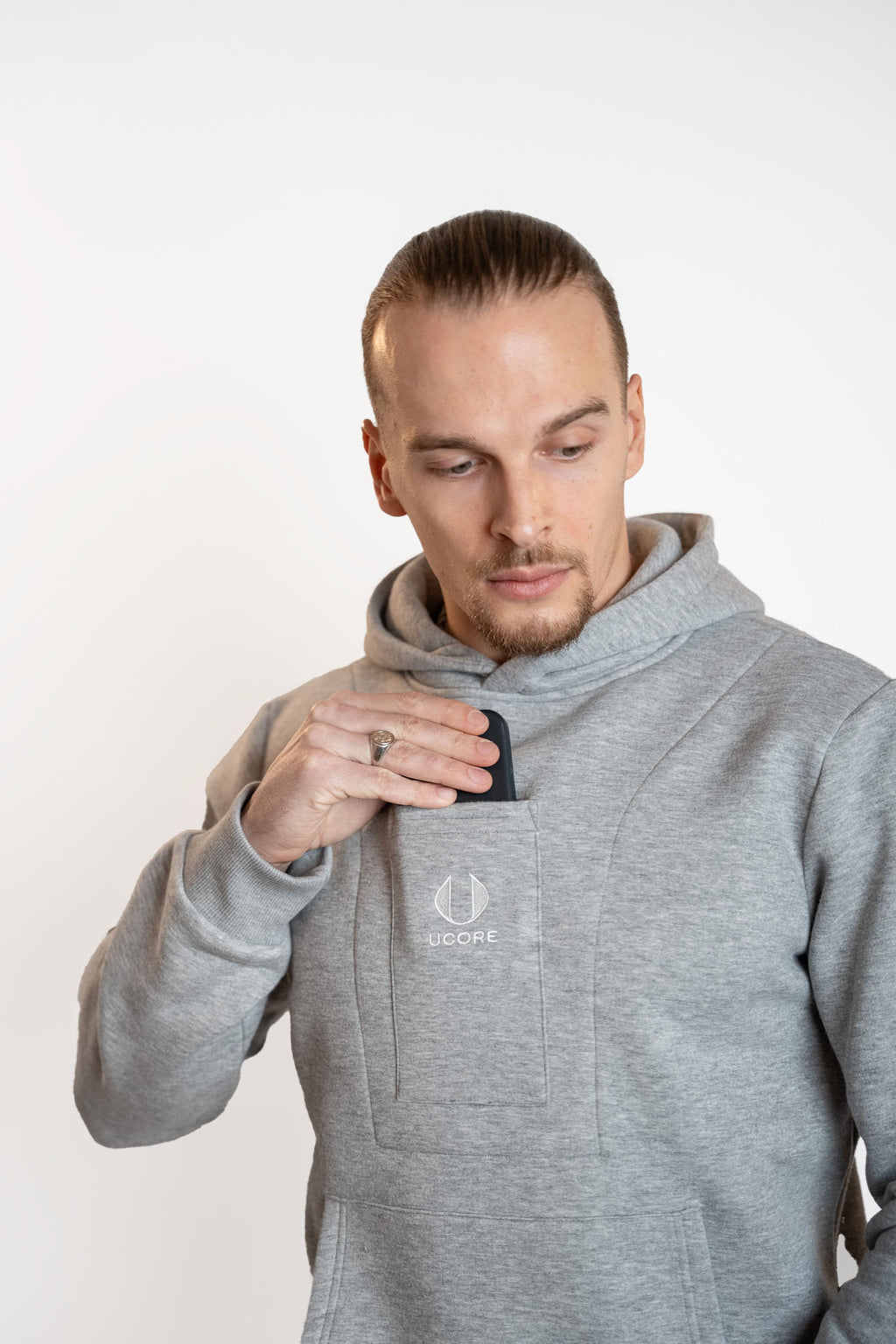 model putting phone into men's grey hoodie central pocket