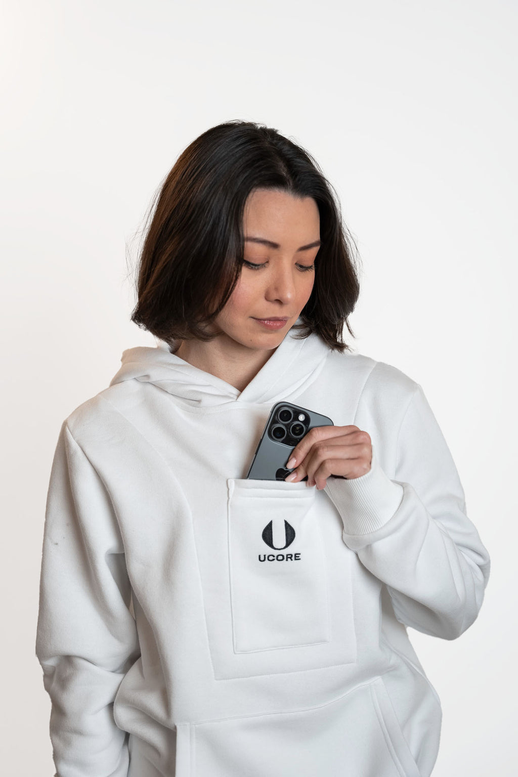 model taking phone out of phone pocket of ucore's white women's hoodie